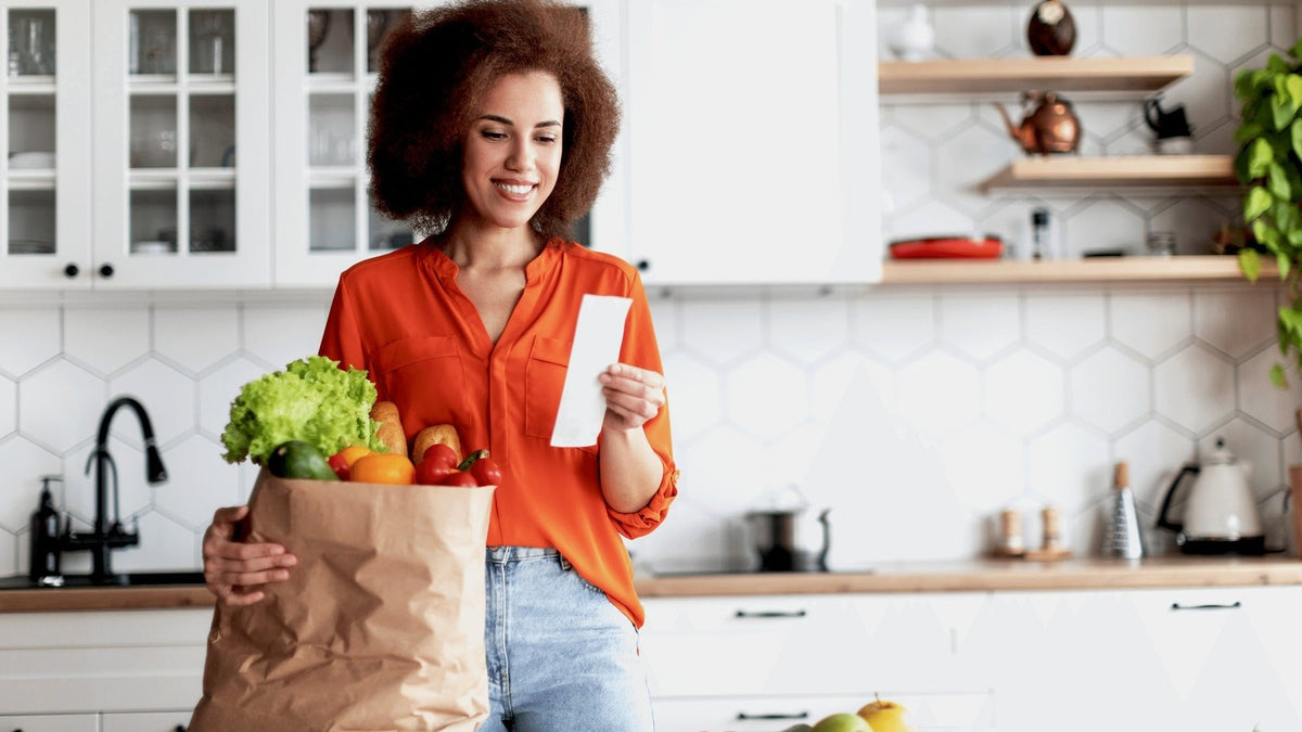 Woman unpacking groceries in a bright kitchen, the everyday routine a well-chosen NMN supplement fits into