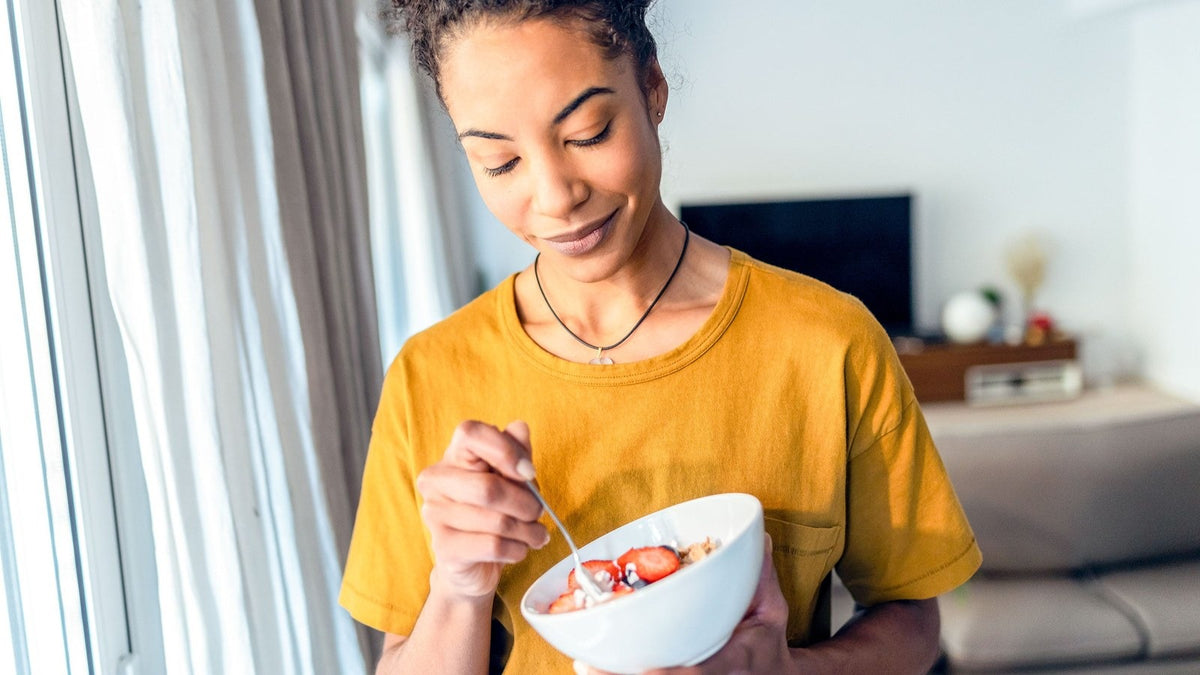Woman eating a small bowl of yogurt and strawberries at home while on GLP-1