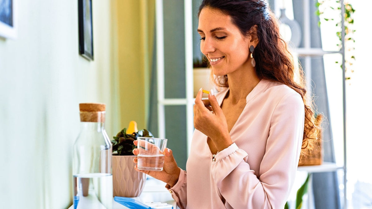 Woman taking an L-glutathione capsule with a glass of water, L-glutathione vs reduced vs liposomal glutathione